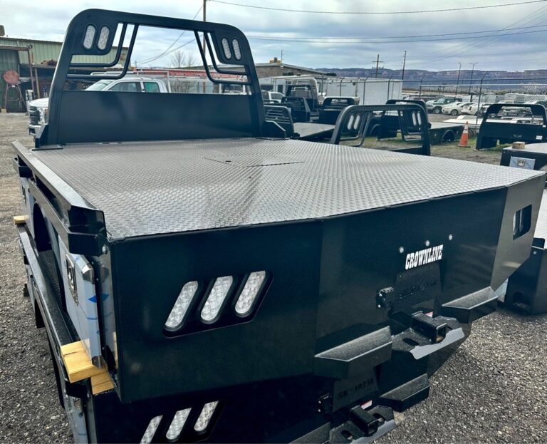Black Crownline flatbed truck bed with diamond plate deck and headache rack, parked on gravel