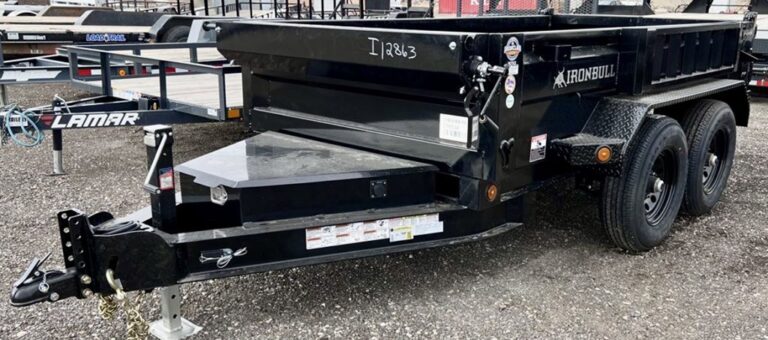 Black Iron Bull dump trailer with dual axles parked on gravel lot with other trailers visible in background.