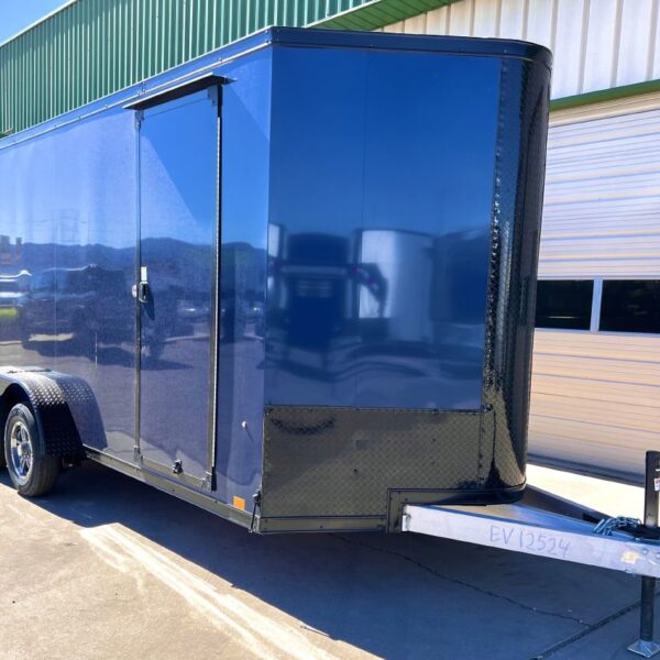 Dark blue enclosed cargo trailer with side door, dual axles, and diamond plate trim parked outside