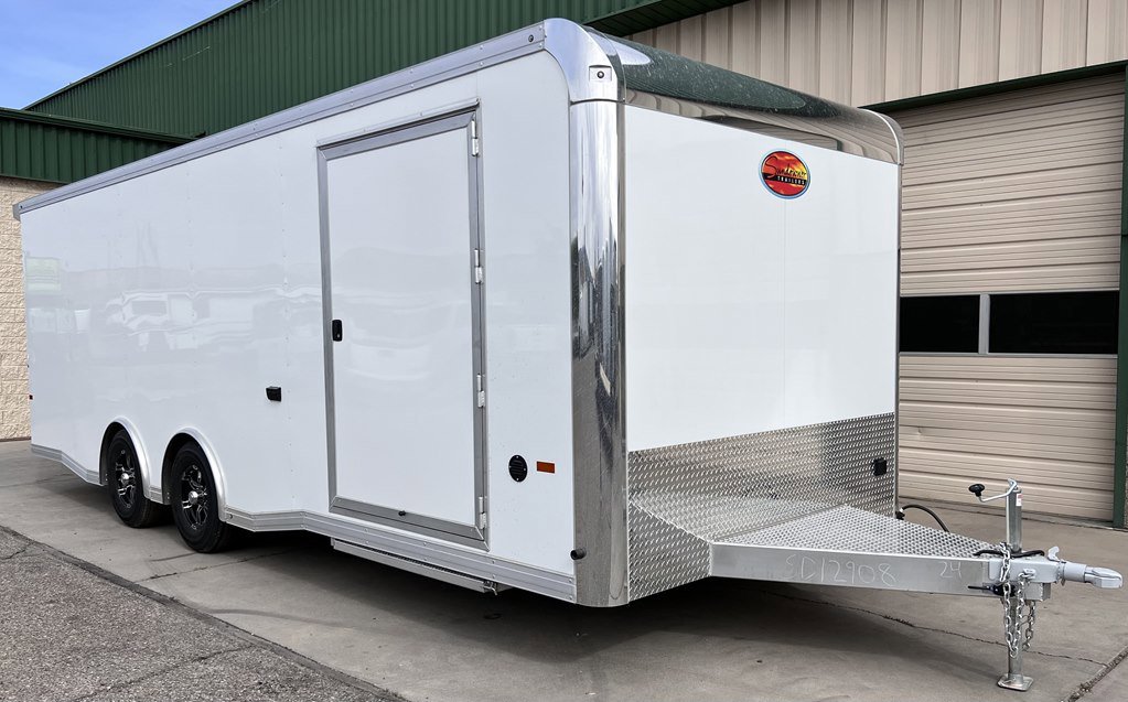 Large white enclosed tandem-axle cargo trailer with shiny rounded front corners, diamond-plate lower section, side door, and a polished aluminum tongue