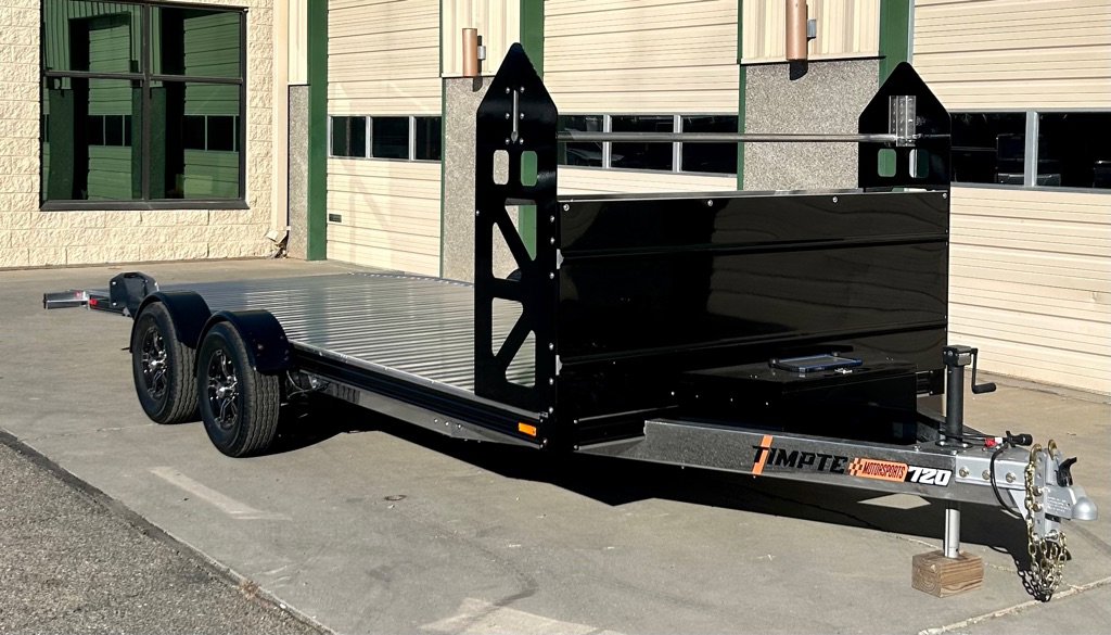 Silver Timpte EZ Load T20 trailer with black front toolbox, parked outside building with garage doors.