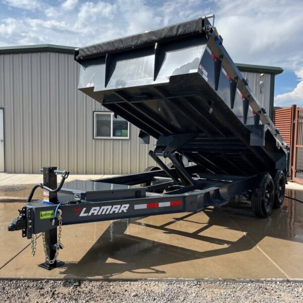 Dark blue Lamar dump trailer with raised bed, dual axles, tarp system, and red-white safety stripes