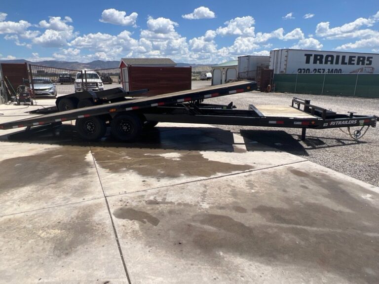 Black PJ tilt trailer with deck raised, parked on concrete trailer sales lot