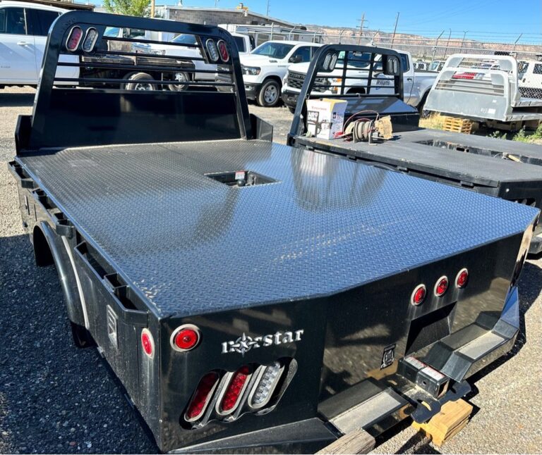 Black Norstar flatbed truck bed with diamond plate deck and headache rack on gravel lot